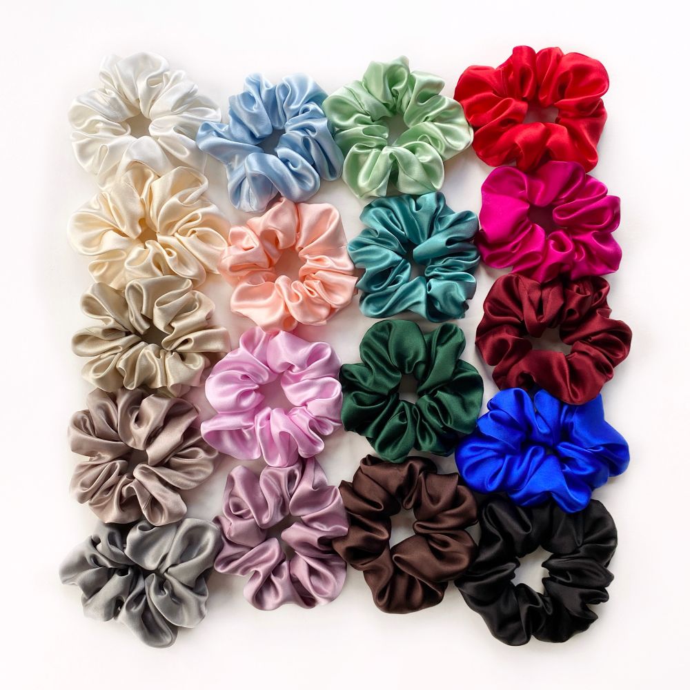 Assorted colorful mulberry silk satin scrunchies and hair ties arranged in a grid on a white background