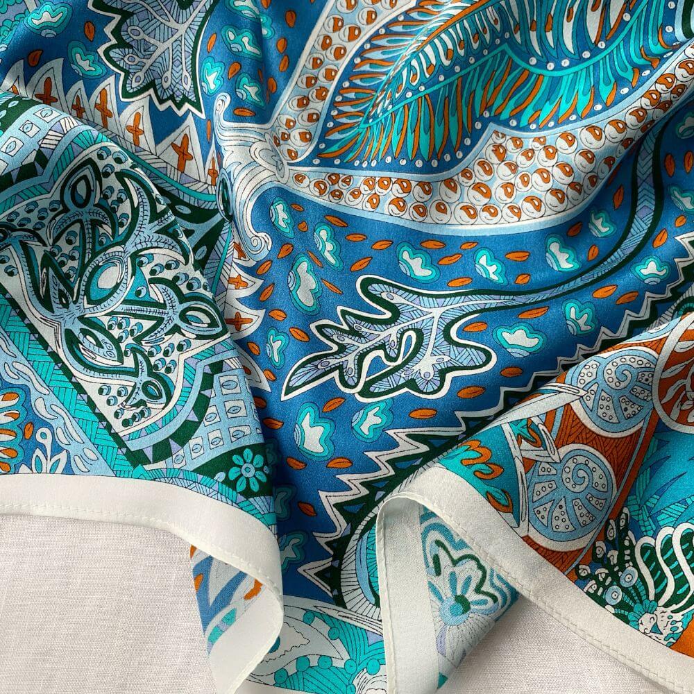 Close-up of colorful patterned silk scarf with blue, green, and orange colors.