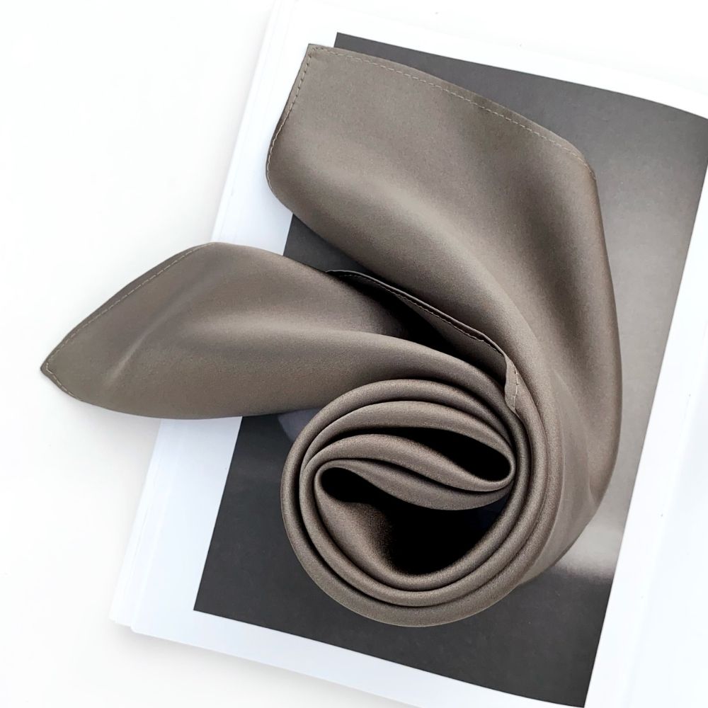 Rolled dark taupe Mulberry silk satin scarf on open magazine page