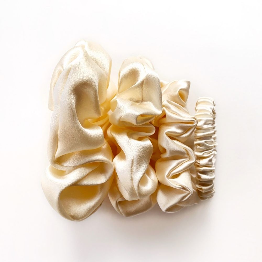 Cream-colored mulberry silk satin scrunchies and hair ties on a white background