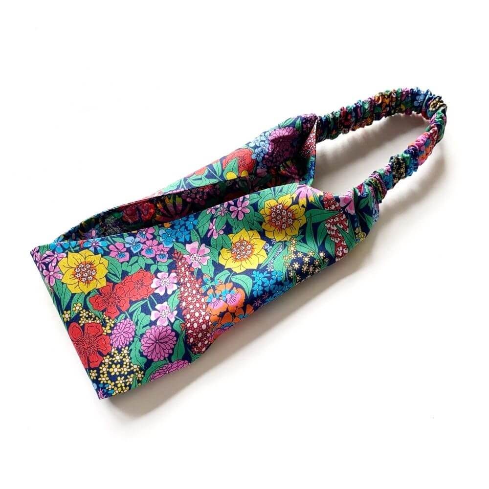 Liberty Ciara floral cotton headband arranged in a curved shape, showing the elastic back and vibrant multicolour design.