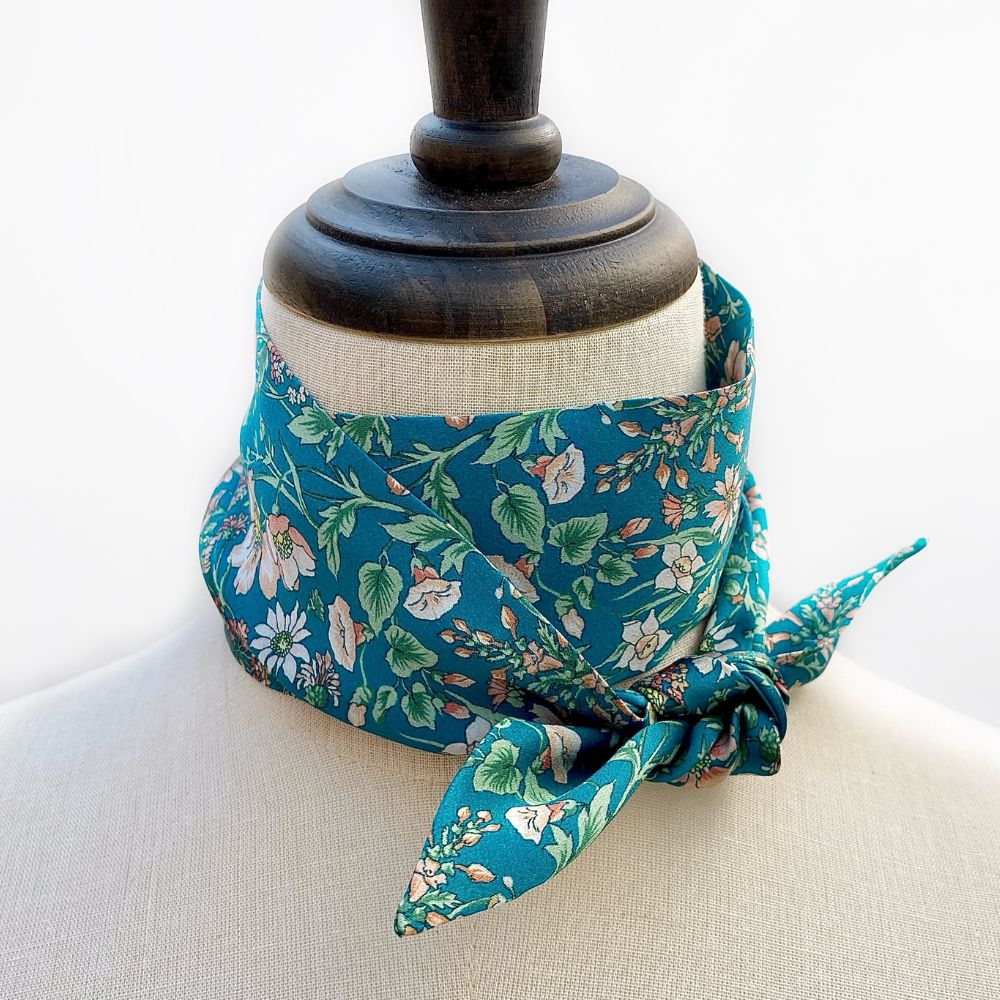 Floral print Liberty silk skinny scarf tied on a mannequin's neck with a white background