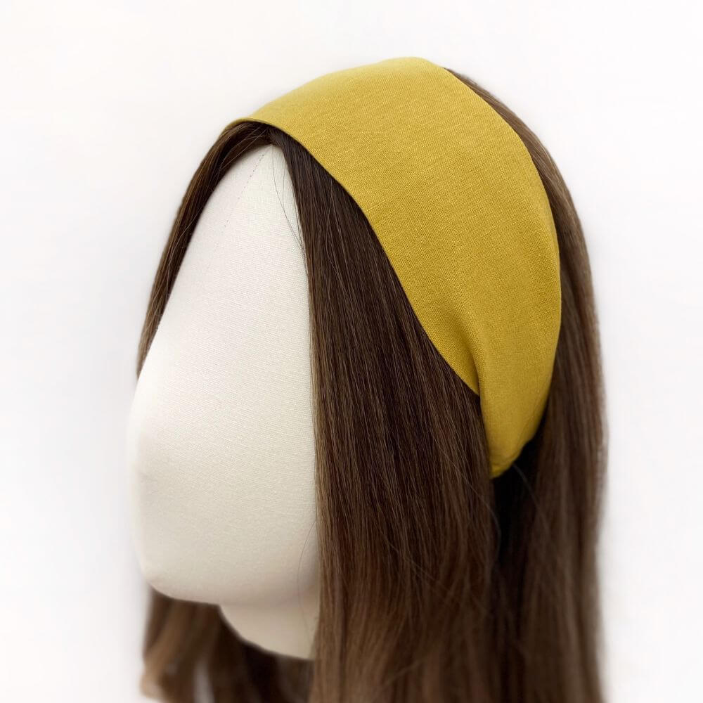 mustard yellow linen headband worn by a mannequin head on a white background