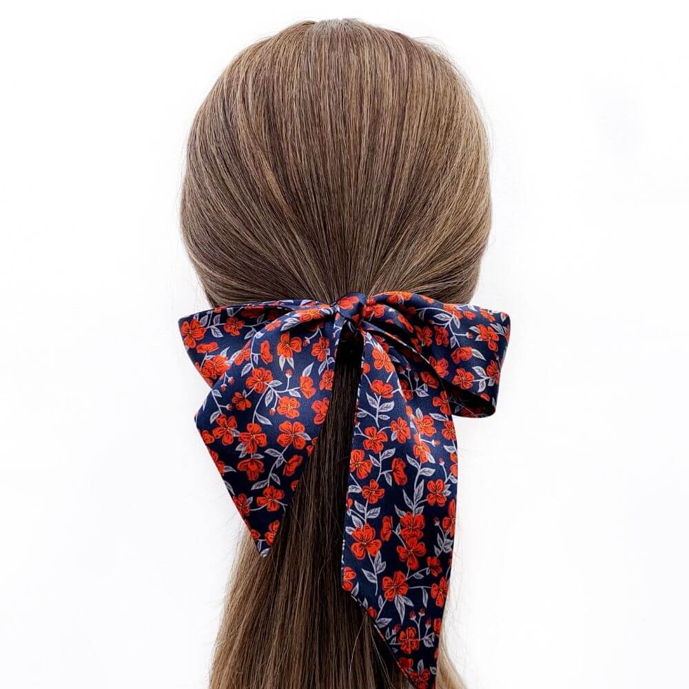 liberty silk skinny scarf wear as a hair bow with floral pattern tied around a ponytail on a white background