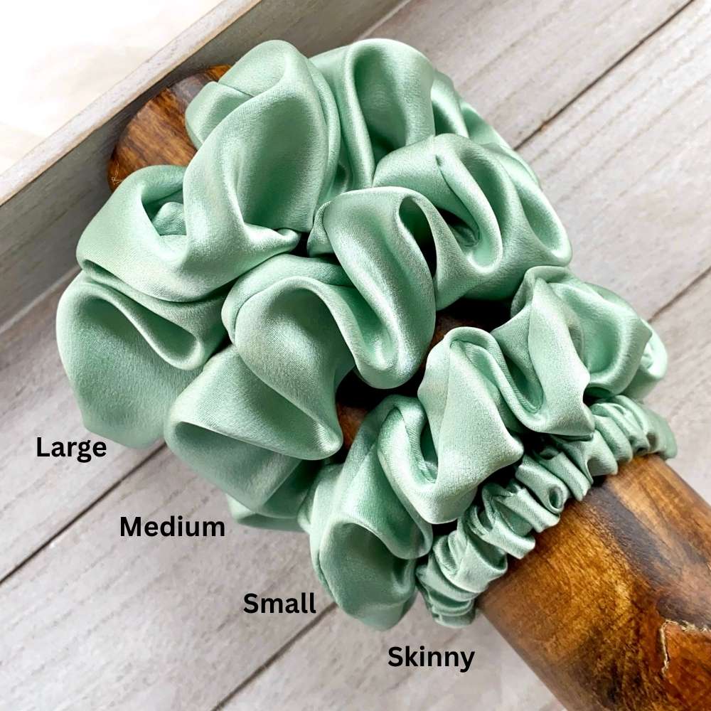 Set of four green silk scrunchies on a wooden handle with size labels.