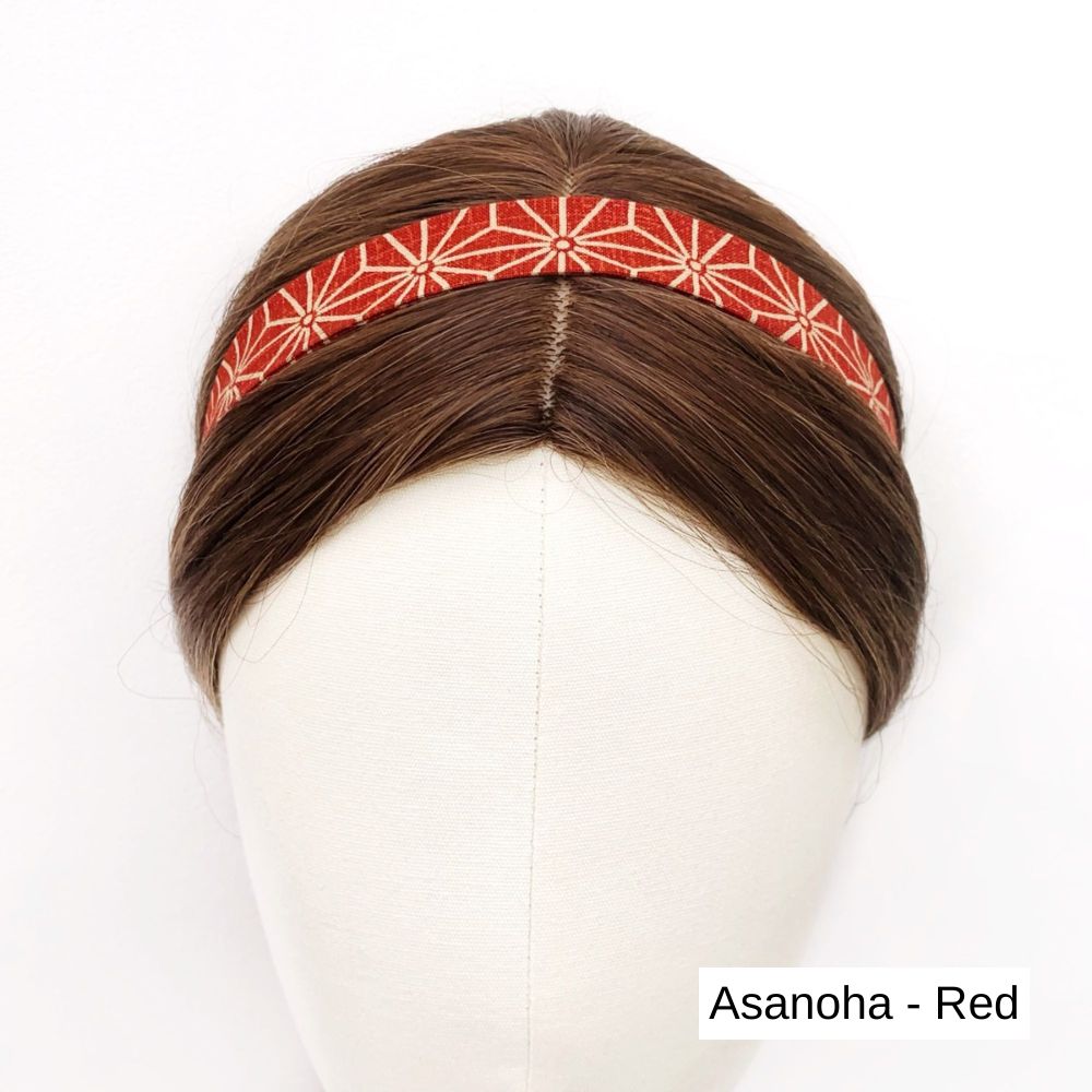 Red cotton skinny headband with white patterns on a mannequin head against a white background