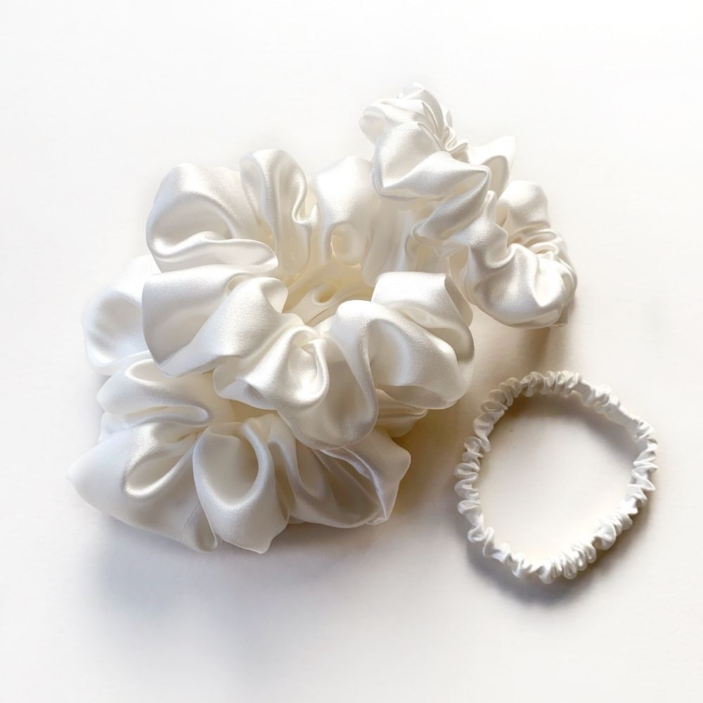 Set of white mulberry silk satin scrunchies and silk hair ties on a white background