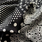 Close-up detail of a black and white polka dot and paisley print mulberry silk square scarf.