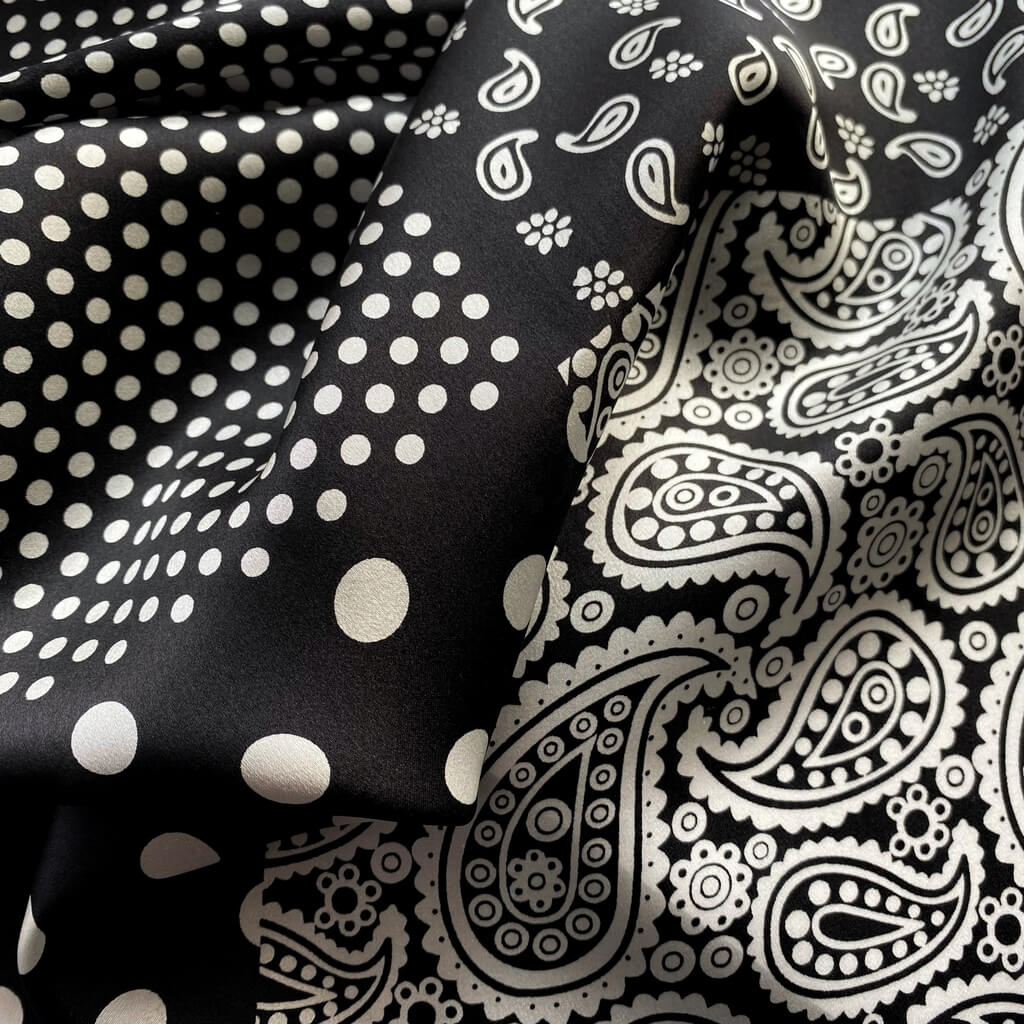 Close-up detail of a black and white polka dot and paisley print mulberry silk square scarf.