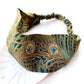 A  Liberty London mulberry silk satin headband featuring a detailed peacock feather pattern in teal green, gold, and brown on a white background.