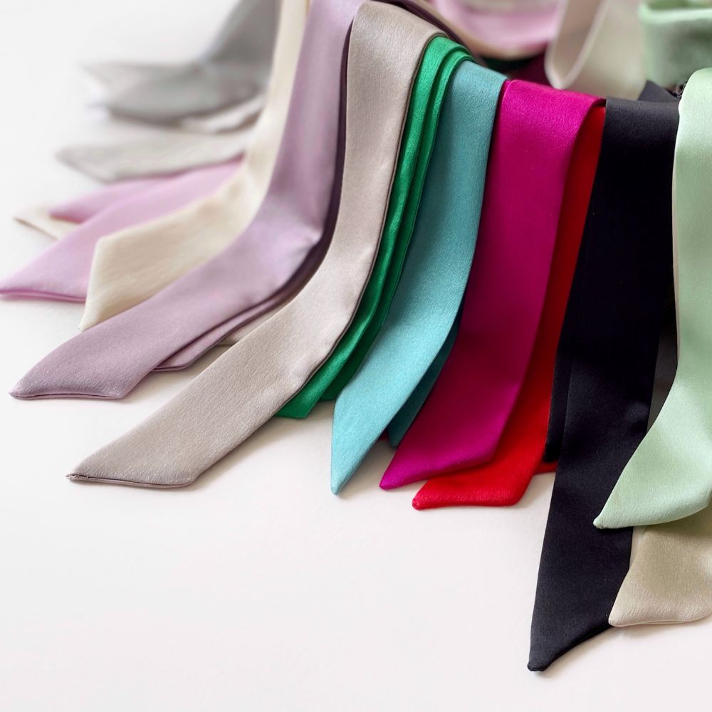 Set of colorful mulberry silk skinny scarf ribbons in various shades on a neutral background
