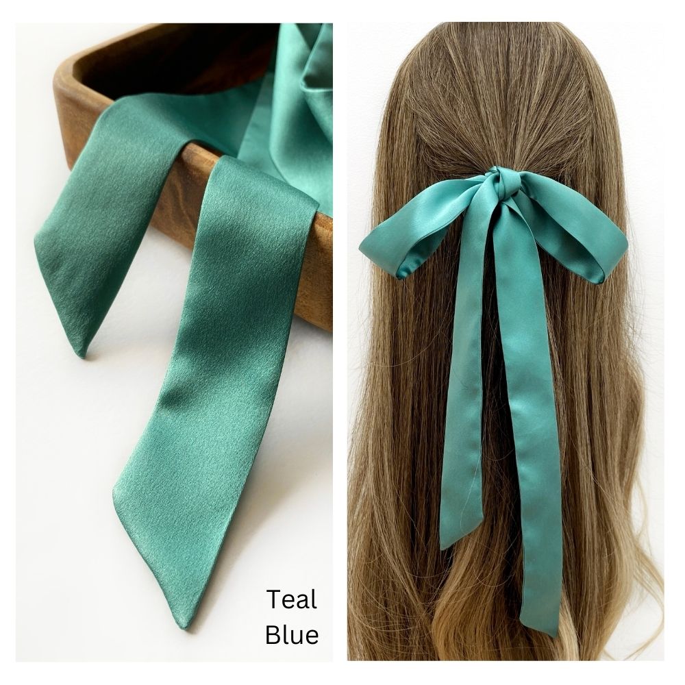 A teal blue mulberry silk satin skinny ribbon scarf tied as a hairbow, styled against a crisp white background.