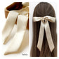 An ivory mulberry silk satin skinny ribbon scarf tied as a hairbow, styled against a crisp white background.