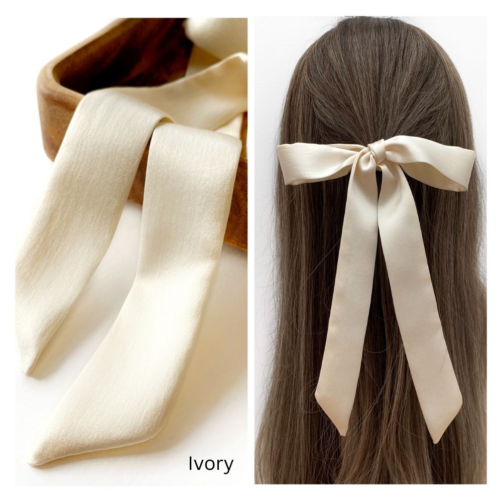 An ivory mulberry silk satin skinny ribbon scarf tied as a hairbow, styled against a crisp white background.