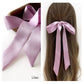 A lilac mulberry silk satin skinny ribbon scarf tied as a hairbow, styled against a crisp white background.