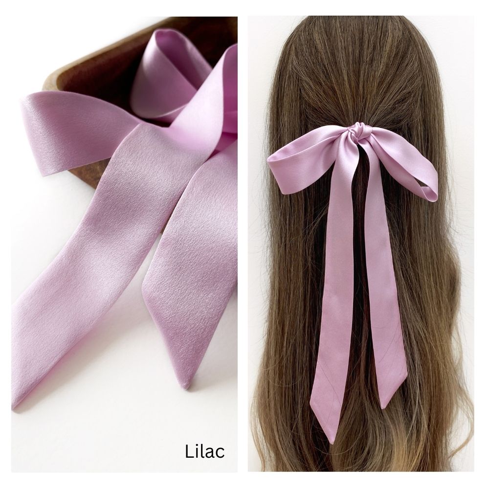 A lilac mulberry silk satin skinny ribbon scarf tied as a hairbow, styled against a crisp white background.