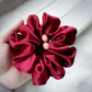 Red scrunchie held in a hand against a light wooden background