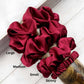 Set of red scrunchies labeled with size on a white surface