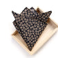 folded blak floral print japanese cotton pocket square hankerchief displayed on a light wood tray against a white background.