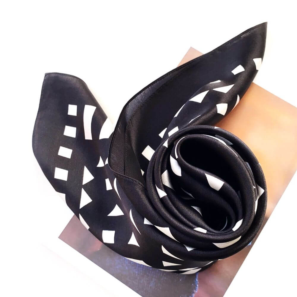 Black and white geometric mulberry silk square scarf swirled on a white background
