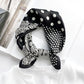 Black mulberry silk square scarf with white paisley and polka dot pattern tied into a neckerchief on a white linen shirt collar.