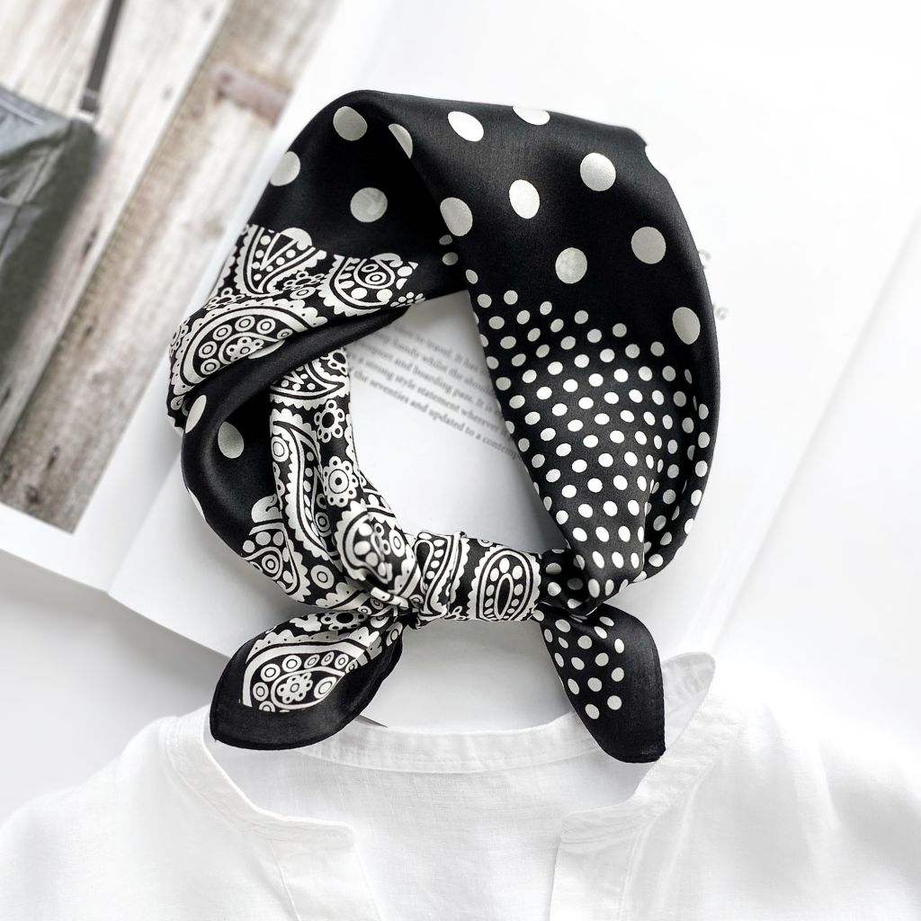 Black mulberry silk square scarf with white paisley and polka dot pattern tied into a neckerchief on a white linen shirt collar.