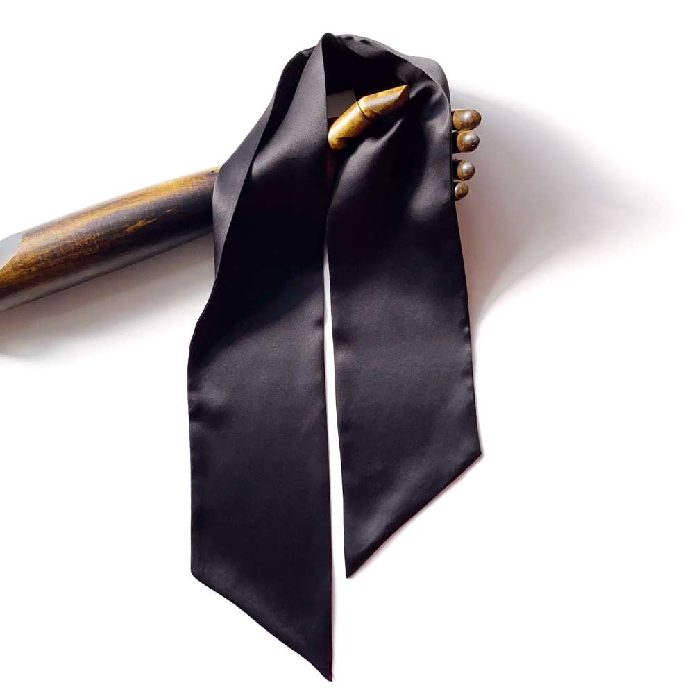 Black silk satin scarf draped over a wooden hand on a white background