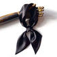 Black mulberry silk satin scarf tied around a wooden hand on a white background