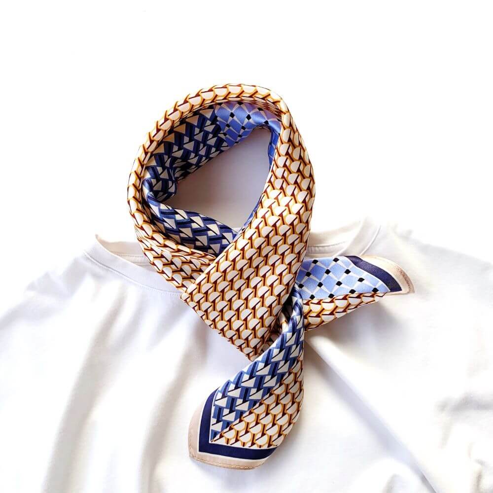 Blue & caramel geometric patterned mulberry silk neck scarf on a white t-shirt