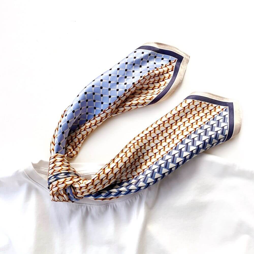 Blue & caramel geometric patterned silk scarf tied and placed on a white t-shirt