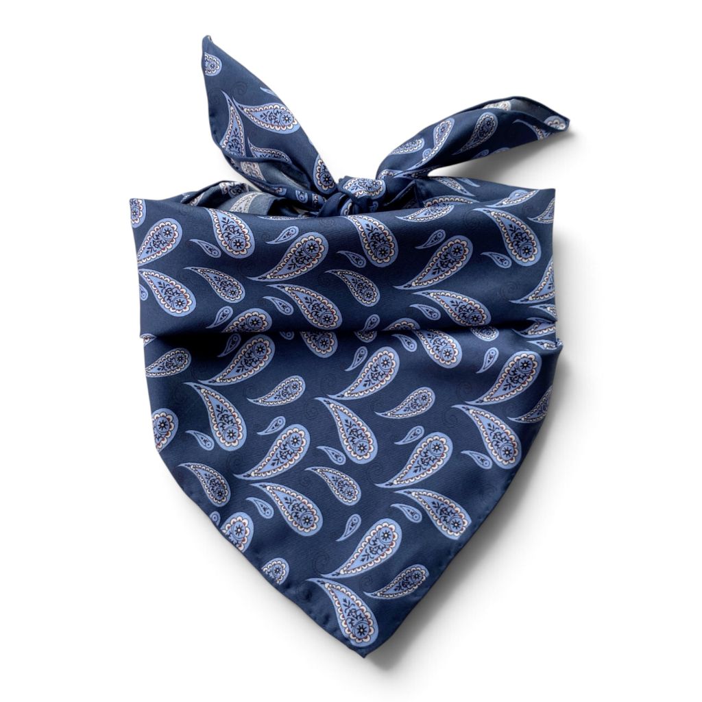 Blue paisley print mulberry silk square scarf tied at the back, placed on a white background