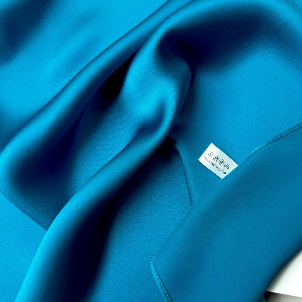 Close-up of Kingfisher Blue Mulberry silk satin scarf with a visible brand label.