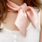 Model wearing blush pink satin silk neck scarf tied in a bow