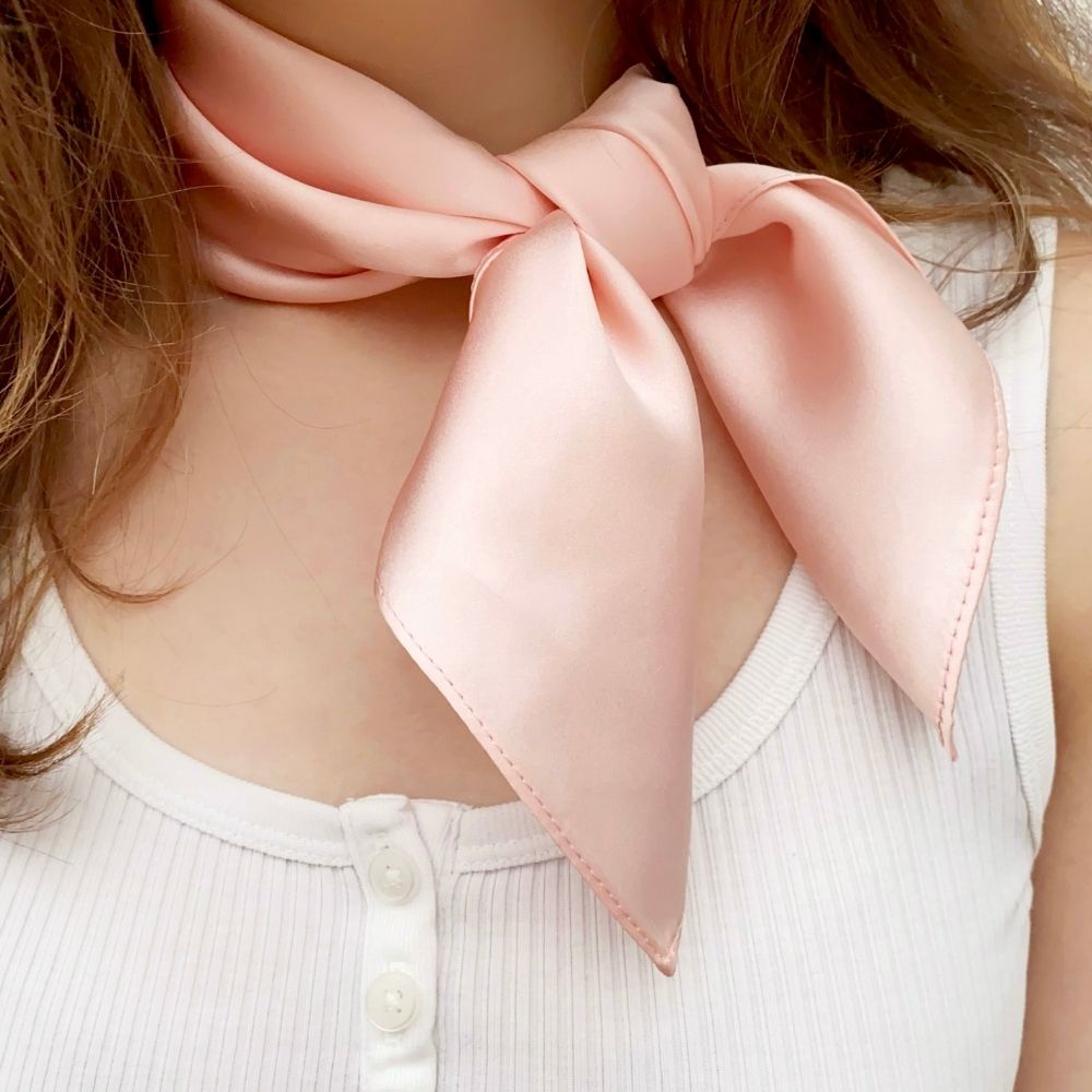 Model wearing blush pink satin silk neck scarf tied in a bow