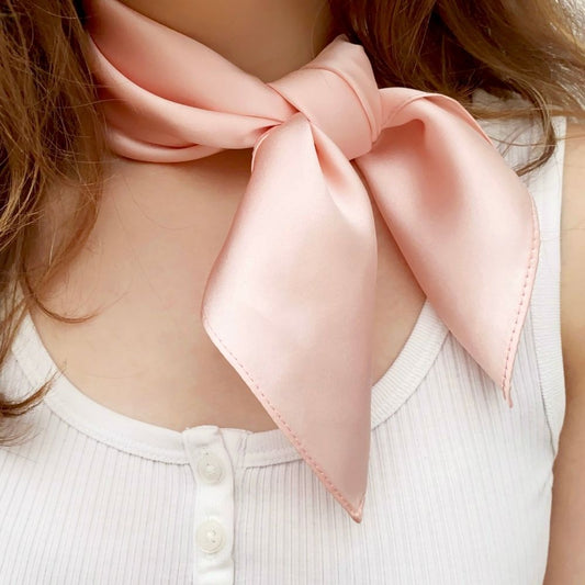 Model wearing blush pink satin silk neck scarf tied in a bow