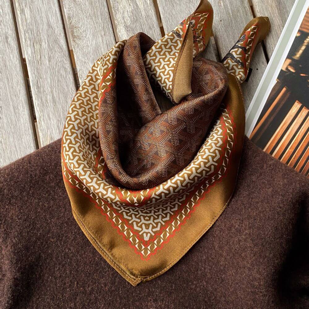 Brown Japanese-patterned mulberry silk square scarf elegantly draped over a knit jumper.