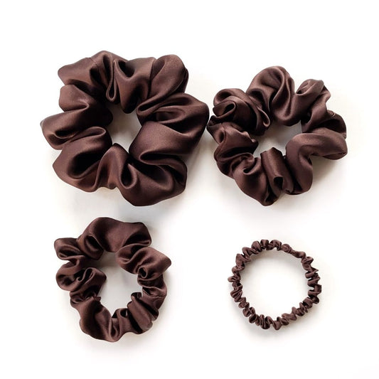 Four brown mulberry silk satin scrunchies and silk hair ties on a white background