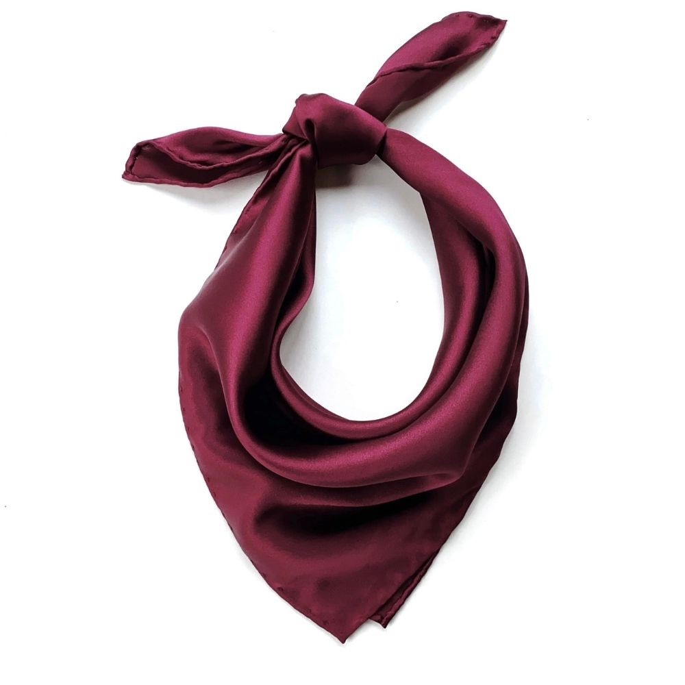 Burgundy silk scarf tied in a knot on a white background