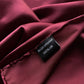 Close-up of burgundy silk fabric with a 'RIVER MINAMI' and 100% silk washing label 
