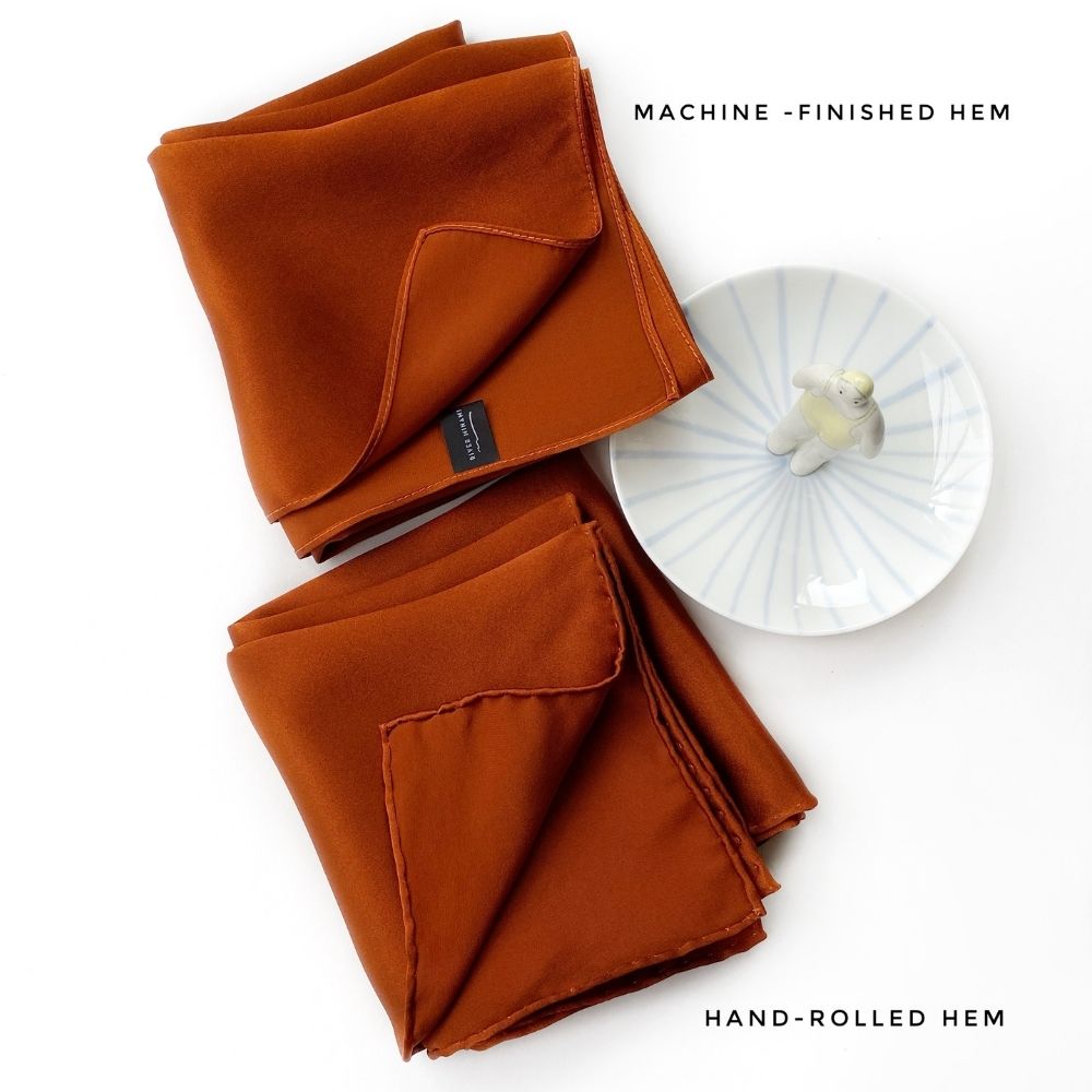 Machine-finished and hand-rolled hem comparison in burnt orange silk