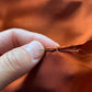 Hand-stitching process on burnt orange Mulberry silk hand-rolled hem