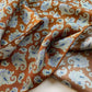 Close-up of caramel orange brown mulberry silk bandana scarf with white paisley pattern