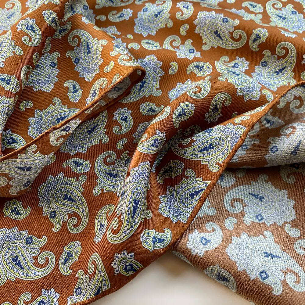 Close-up of caramel orange brown mulberry silk bandana scarf with white paisley pattern