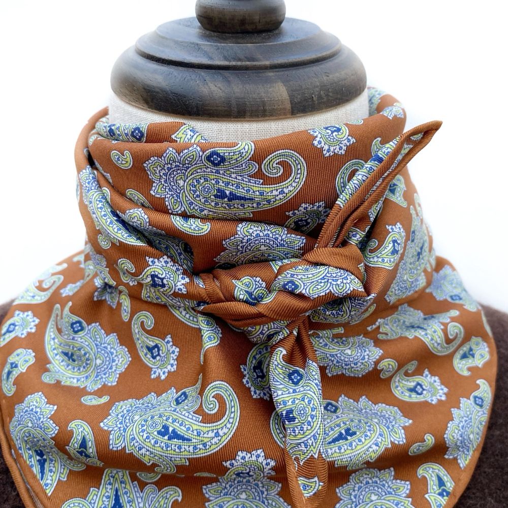 caramel orange brown paisley patterned mulberry silk square bandana scarf on a mannequin with a white background