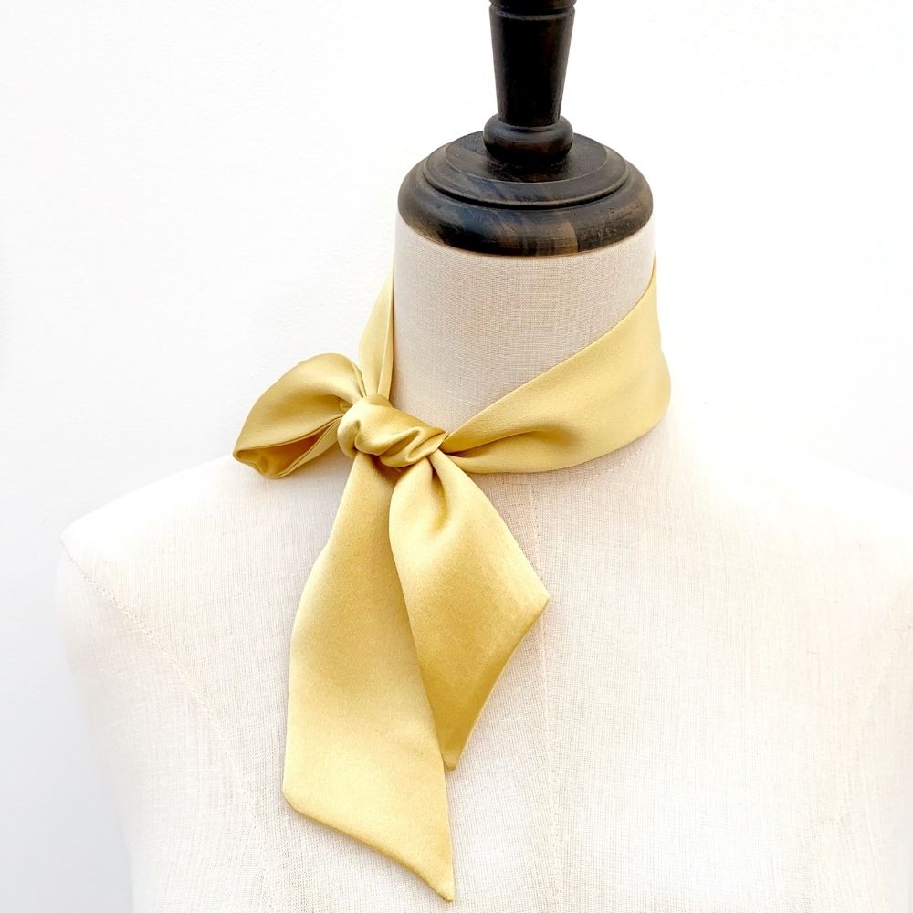 light yellow mulberry silk satin skinny scarf tied around mannequin's neck