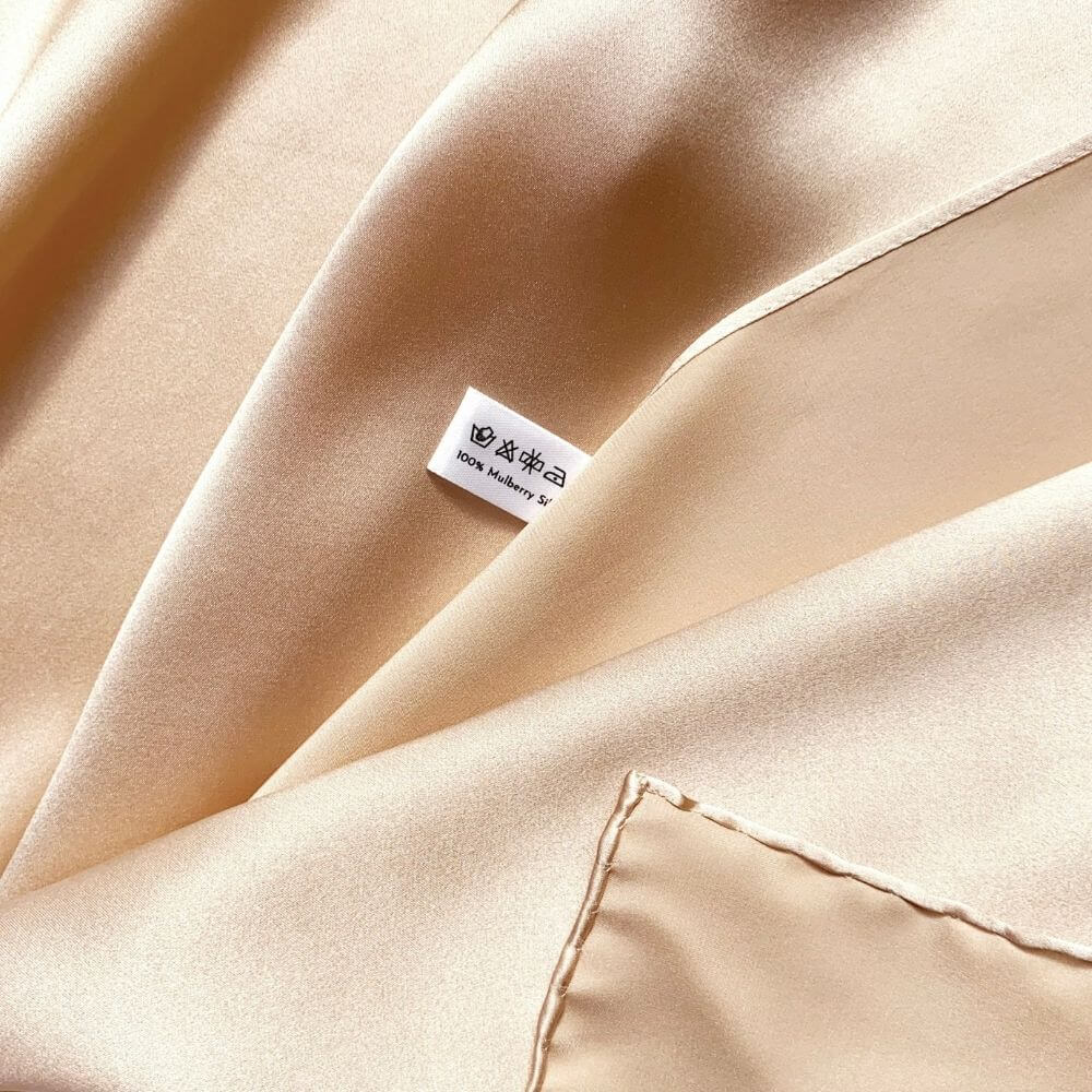 Close-up of champagne beige silk scarf with a river minami washing label.