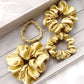 Set of soft yellow mulberry silk satin scrunchies on a wooden surface