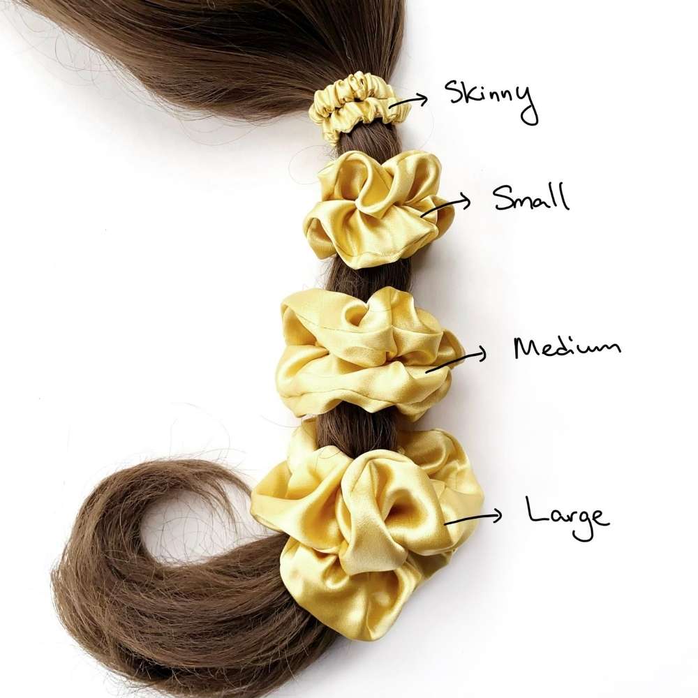 soft yellow mulberry silk satin scrunchies of different sizes on a ponytail with labeled sizes.