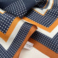 Close-up of geometric patterned mulberry silk square scarf with a visible brand tag, featuring navy, brown, and white colors.