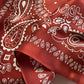close up of a red mulberry silk bandana with white paisley patterns